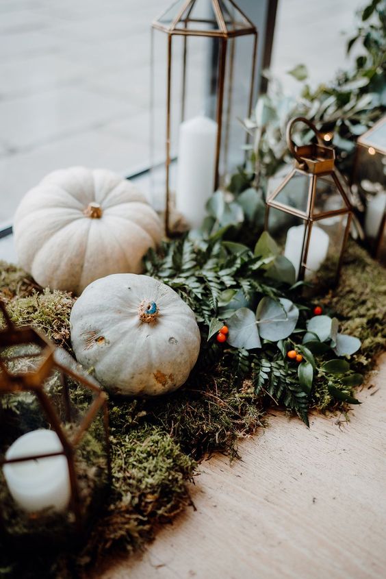 fall wedding decor with white pumpkins on moss, greenery, berries and candle lanterns is amazing