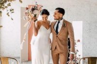 minimalist couple’s looks with a rust suit and white sneakers, a white slip maxi wedding dress with a train for the fall
