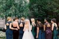 mismatching jewel tone bridesmaids’ dresses in green, navy, burgundy and purple with embeliishments