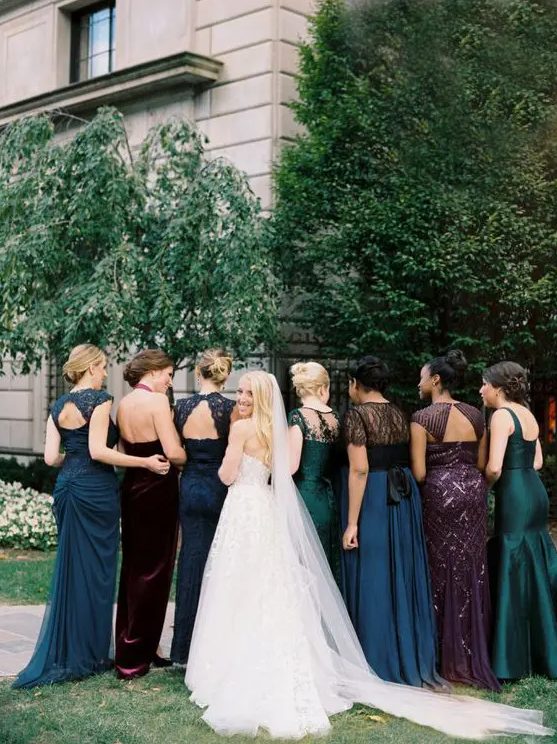 mismatching jewel tone bridesmaids' dresses in green, navy, burgundy and purple with embeliishments