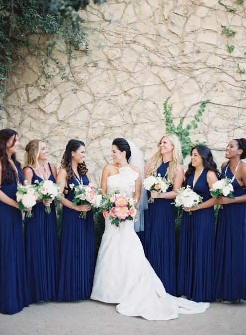 mismatching pleated navy maxi bridesmaid dresses paired with white bouquets create a chic contrasting look