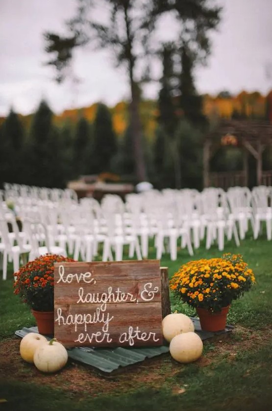 rustic fall wedding decor with a sign, pumpkins, bright potted blooms is a lovely idea for a rustic fall wedding ceremony space