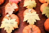 small pumpkins with escort cards shaped as leaves are a cool idea for a fall wedding, they can double as guest favors