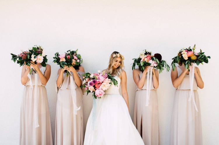 The bride rocked a perfect for a tropical wedding strapless dress and the bridesmaids were wearing different neutral dresses