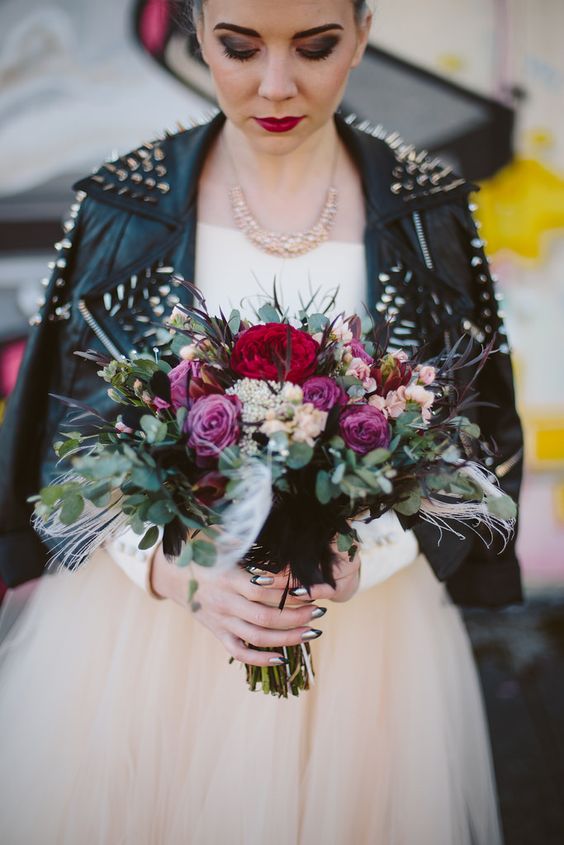 grunge bride in an ivory dress, a spiked leather jacket with bold makeup