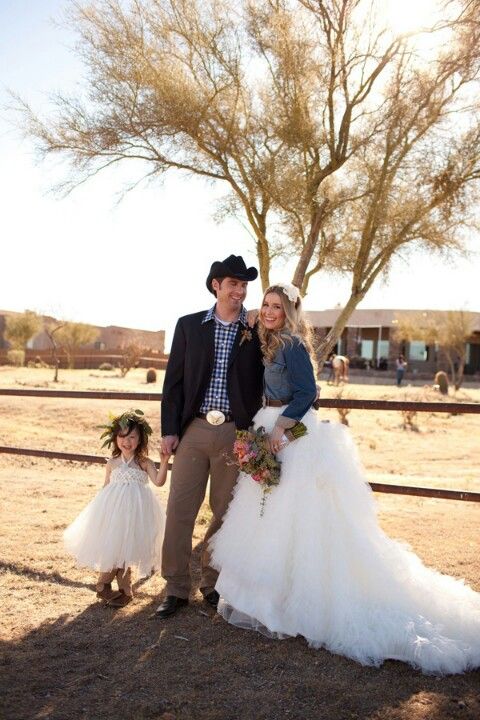 a rustic bridal look with a ruffle wedding dress with a long train and a blue denim jacket plus a brown leather belt