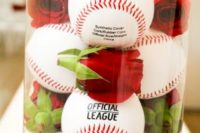 Baseballs and red roses in glass vase