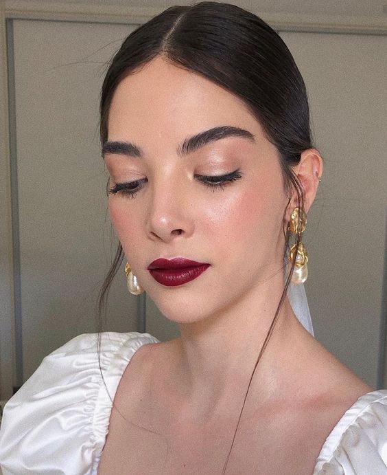 a berry wedding makeup with a dark berry lip, pink blush and eyeshadow plus highlighter for a glam feel
