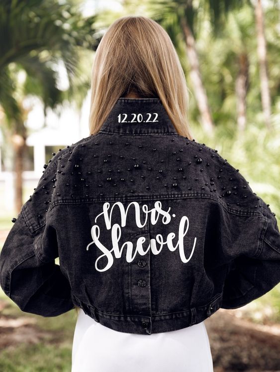 a black denim bridal jacket with black pearl embellished shoulders, white calligraphy and a wedding date is a cool idea