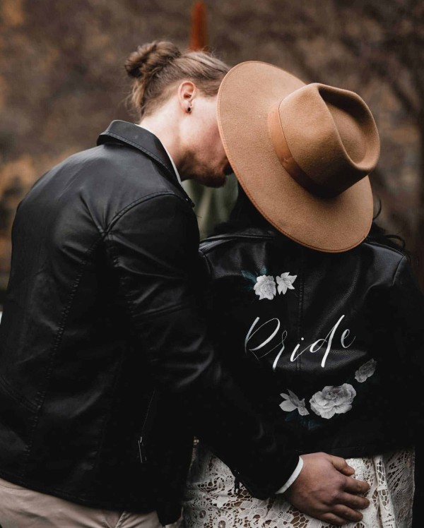 a black painted leather jacket with white blooms and white calligraphy is a lovely accent for a dramatic bridal look