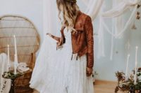 a boho bride in a lace dress and a brown leather jacket with tassels looks gorgeous and very chic