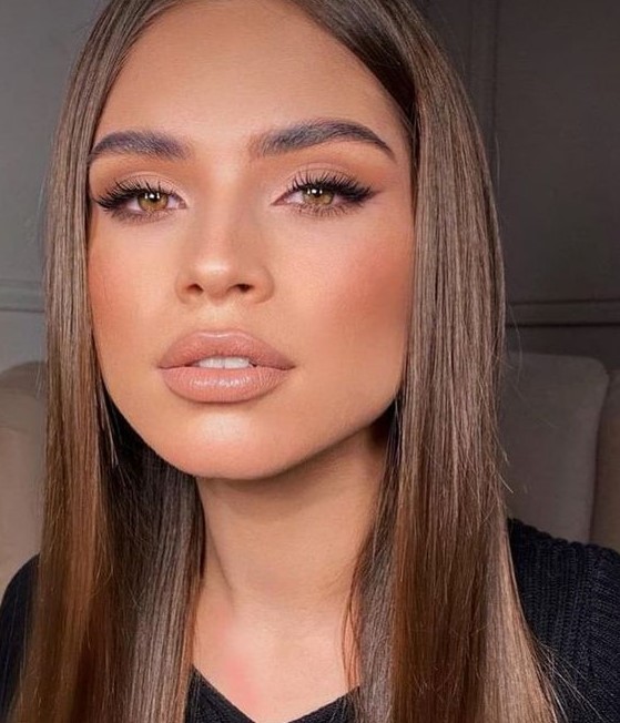 a chic makeup with a blush and eyeshadow, a glossy nude lip and cool eyebrows plus a touch of highlight