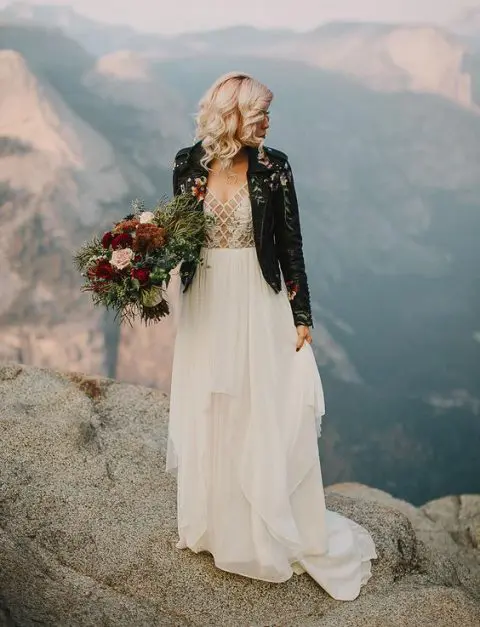 a chic wedding dress with a layered skirt, a sheer and lace applique bodice and a handpainted black leather jacket