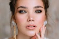 a delicate wedding makeup with a nude lip, a touch of blush, smokey eyes, brushed eyebrows and a touch of highlighter