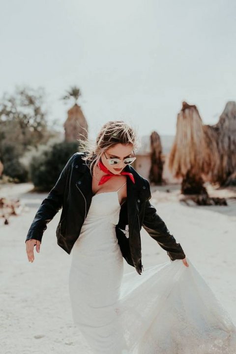 a spaghetti strap sheath wedding dress, a black elather jacket and a touch of red are a lovely combo for a modern bride