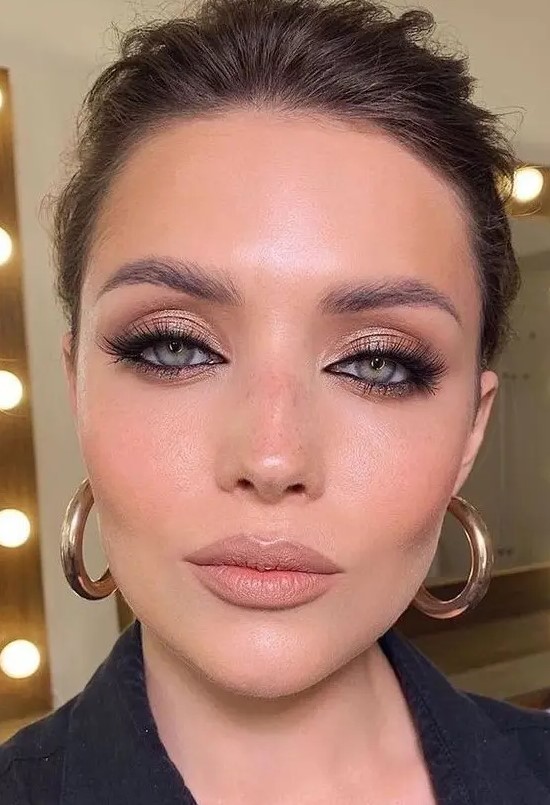 a special occasion makeup with rose gold eyeshadow, accented eyes with faux eyelashes, a nude lip and a touch of blush and highlighter