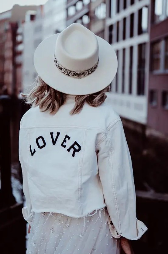 a white denim jacket with black letters and an even edge over an embellished wedding dress for a bold look