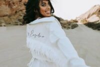 a white denim jacket with white fringe and black calligraphy is a catchy and bold idea for a boho bride