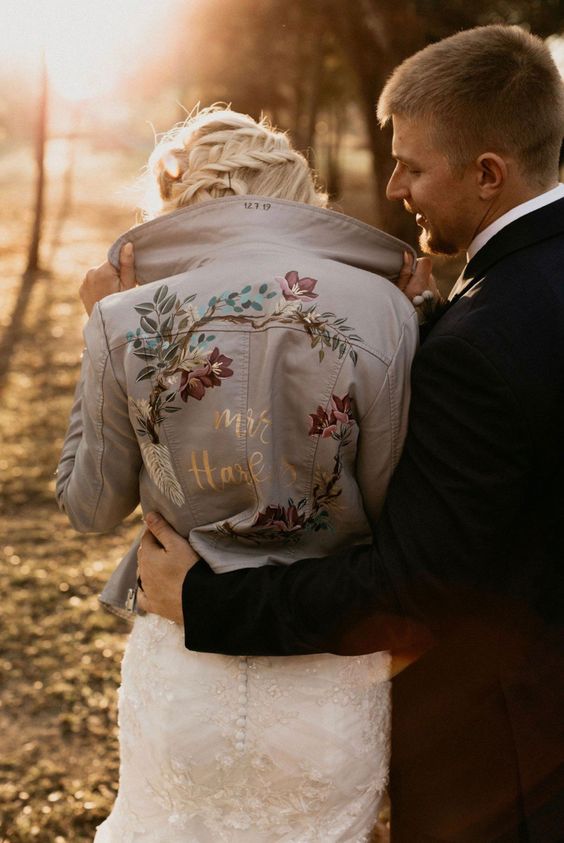 a white painted leather jacket featuring florals and gold calligraphy looks adorable, chic and beautiful and accents the bridal look