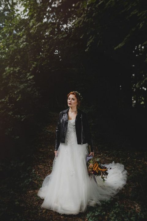 a woodland bride in a princess-style wedding dress and a black leather jacket looks fabulous and very stylish