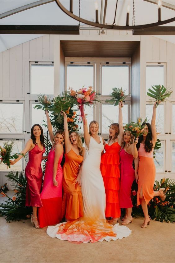bold bridesmaid dresses in orange, hot pink, red and rust and with mismatching designs are amazing for a tropical wedding