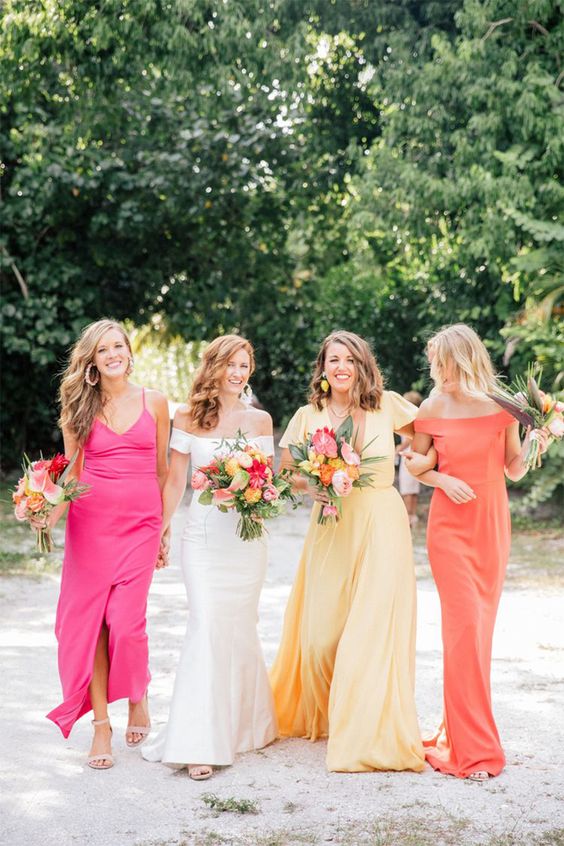 colorful maxi bridesmaid dresses - a pink, yellow and orange one, with mismatching looks are cool for a tropical wedding