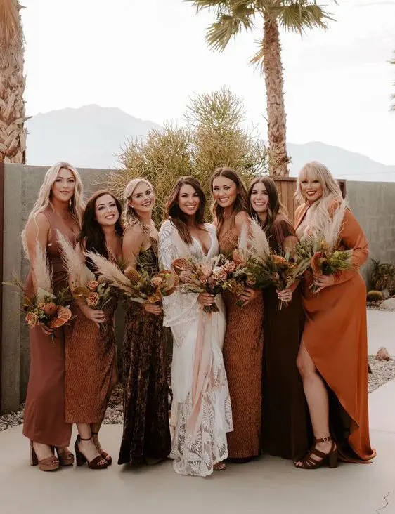 mismatching bridesmaid dresses in chocolate brown, orange, amber, with various necklines and looks for a boho wedding