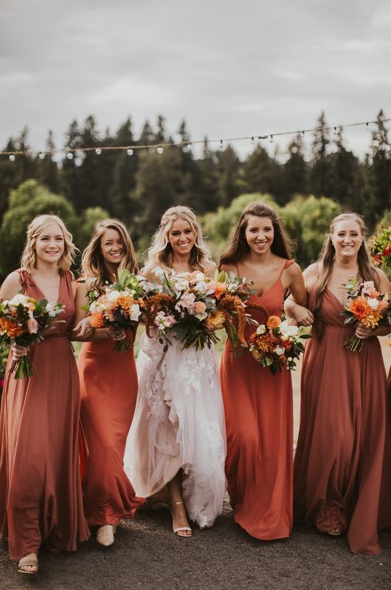 mismatching bridesmaid dresses in orange and rust, with mismatching necklines and detailing for great for a colorful fall wedding