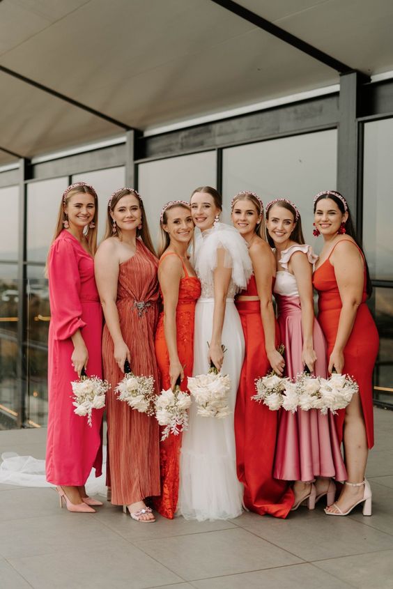 mismatching orange, pink and rust midi and maxi bridesmaid dresses for a bold mismatched bridal party look