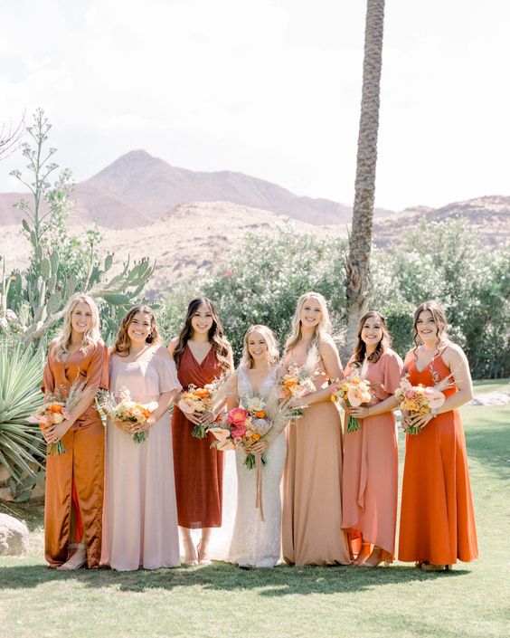 Mismatching pastel, neutral, mustard, orange and rust colored maxi bridesmaid dresses for a chic warm toned boho wedding