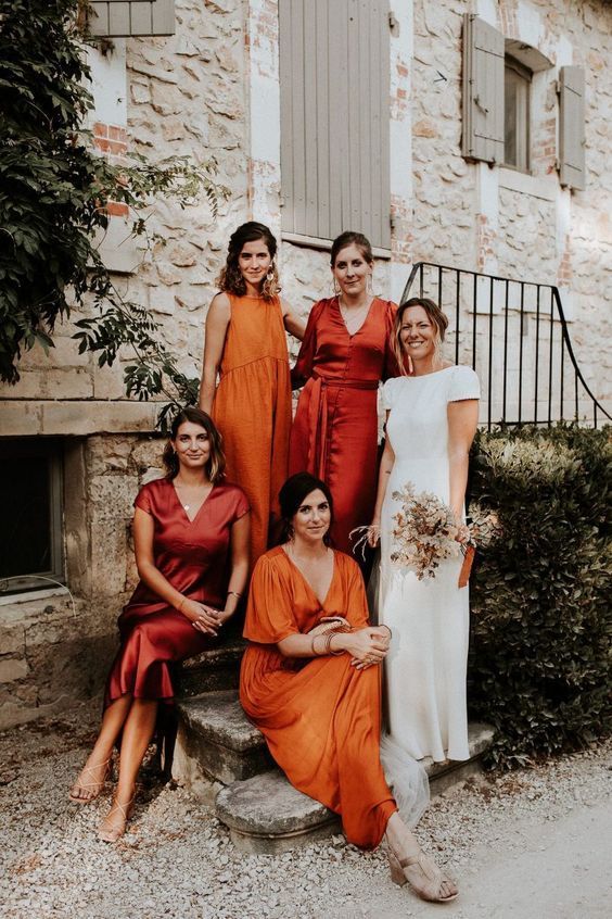 mismatching orange and rust-colored satin maxi and midi bridesmaid dresses with nude shoes for a chic fall wedding