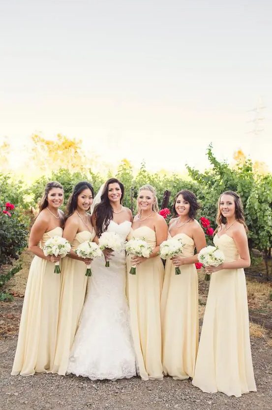 pale yellow strapless maxi bridesmaid dresses with draped bodices and pleated skirts are great for a spring wedding