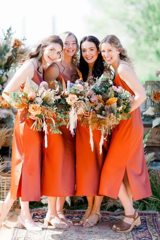 pretty burnt orange midi slip bridesmaid dresses with side slits paired with simple and platform sandals are chic for a boho wedding