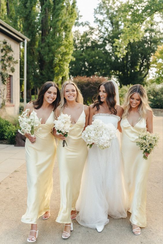 very pale yellow maxi slip bridesmaid dresses and white strappy shoes for a spring or summer wedding