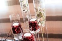 02 tall vases filled with cranberries and topped with floating candles