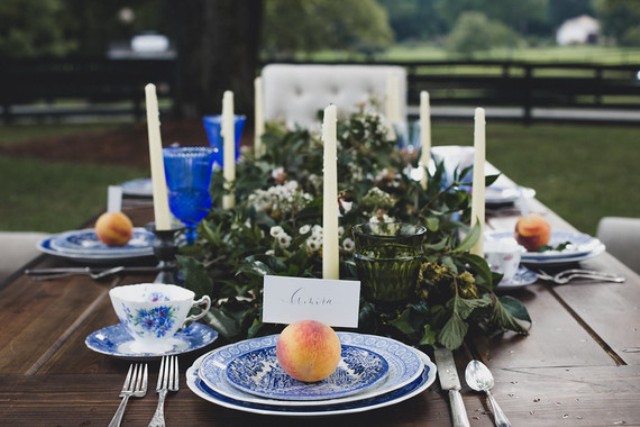 The table setting was done with blue porcelain, greenery, white flowers and peaches