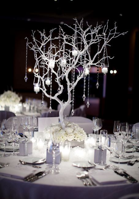all-white table with a white tree made of branches and decorated with candle holders and crystals