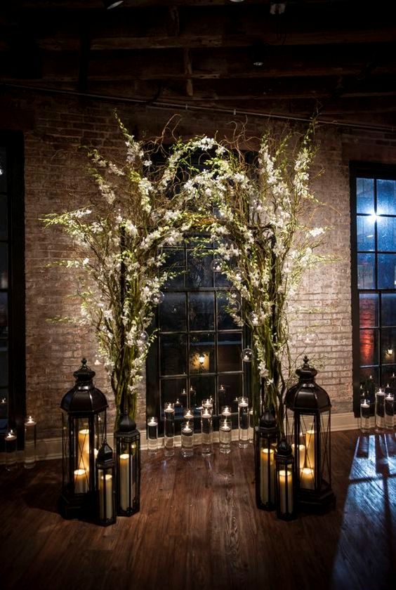 indoor branches and flowers arch with lots of candle lanterns