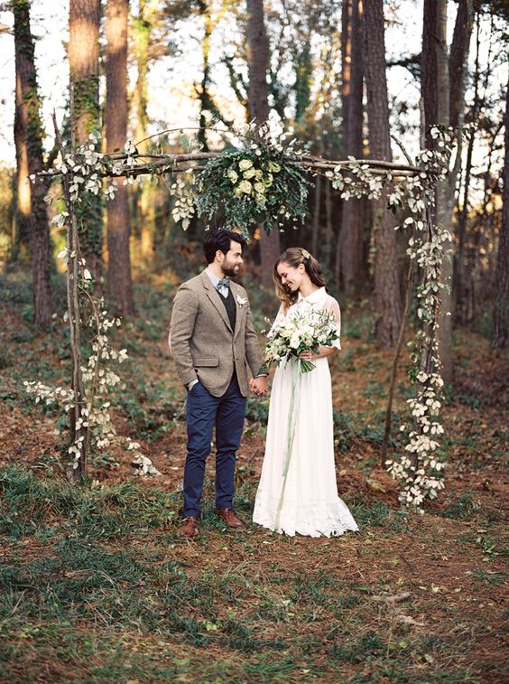 outdoor woodland boho wedding arch decorated with greenery and blooms