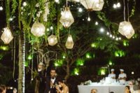 24 geo lanterns glowing in greenery for an outdoor wedding