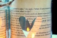 29 mason jars wrapped with book pages and with cutout hearts are amazing lanterns
