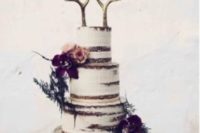 31 wedding cake decorated with dark moody flowers and antlers instead of toppers
