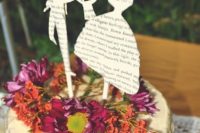 35 wedding cake topped with fresh flowers and cutout silhouettes from book pages