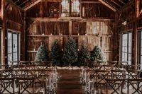 a barn wedding ceremony space with Christmas trees, floating candles adn greenery is a perfect place to tie the knot