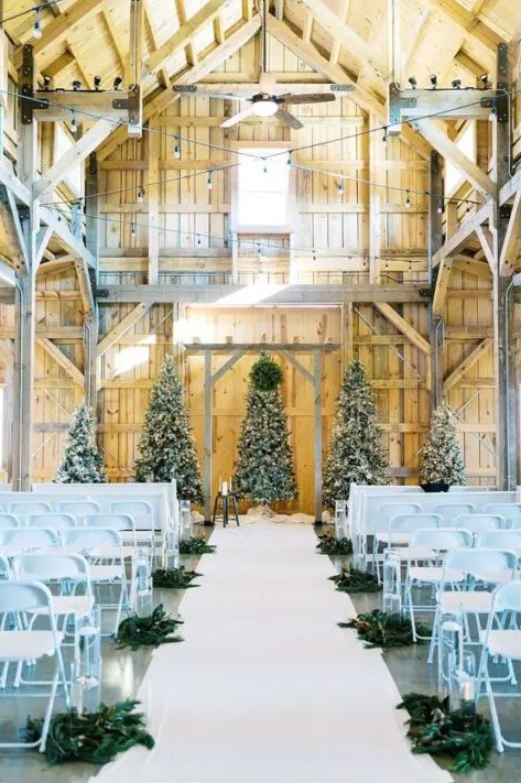 a beautiful Christmas wedding backdrop of five trees dressed up in blues and lights, blue chairs and evergreens on the floor