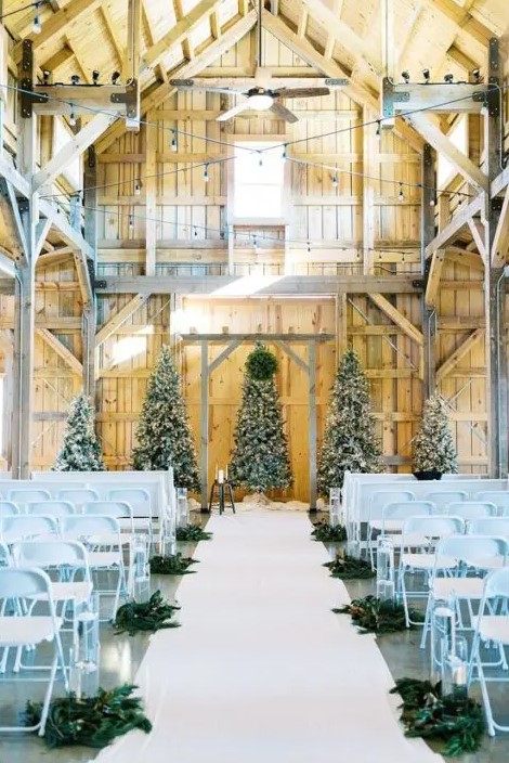 a beautiful Christmas wedding backdrop of five trees dressed up in blues and lights, blue chairs and evergreens on the floor