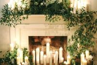 a beautiful fireplace with candles inside, around and on the mantel, with lush greenery and white blooms