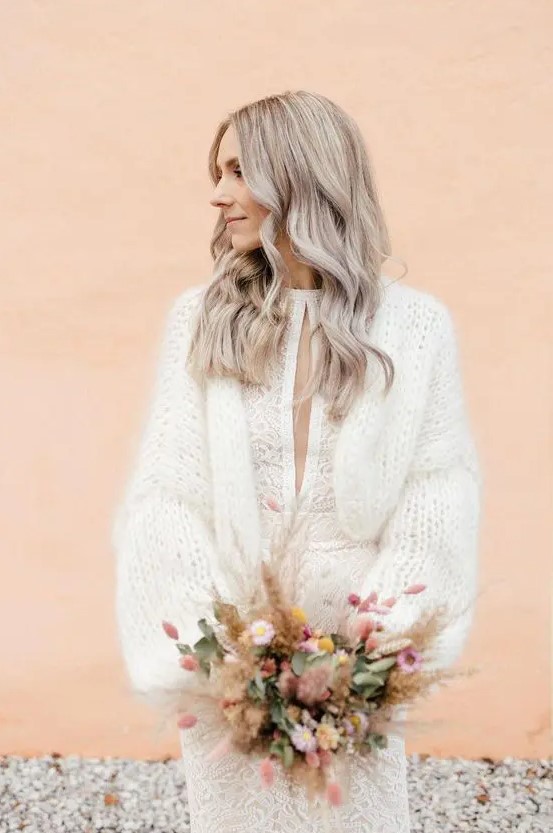 a beautiful patterned wedding dress with a cutout on the front and a warm and soft chunky knit cardigan on top