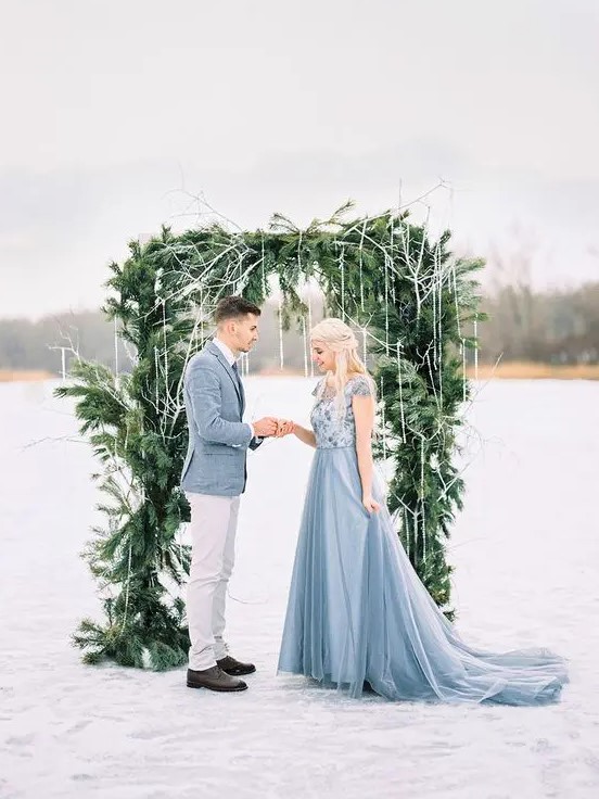 a beautiful winter wedding arch of evergreens with fake icicles hanging gown for a frozen feel