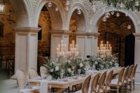 a beautiful winter wonderland wedding space with evergreens, ornaments and candles, matching arrangements on the table and tall candles